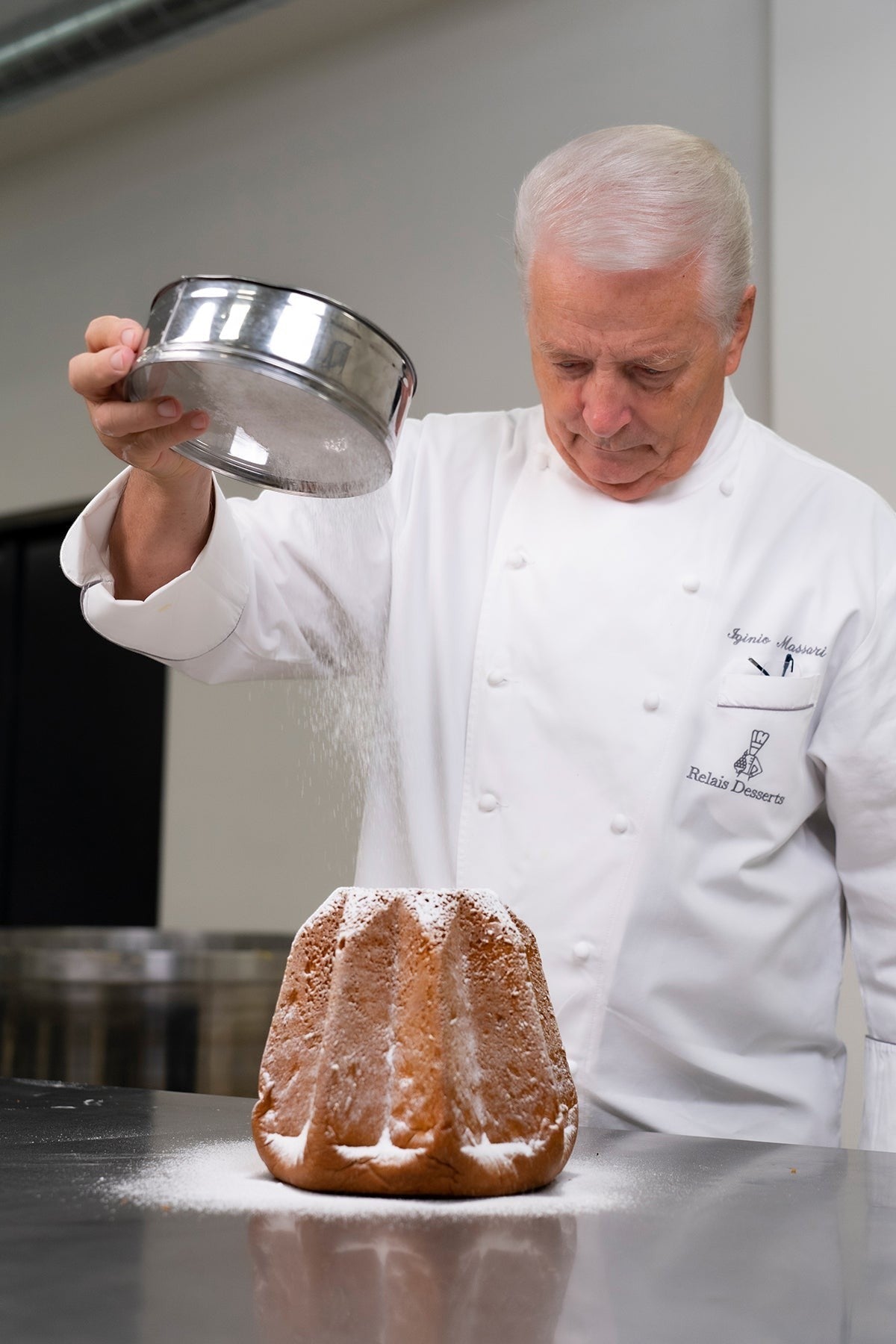 SPLENDIDO Pandoro von Iginio Massari, der Puderzucker über den sternförmigen italienischen Festtagskuchen streut.
